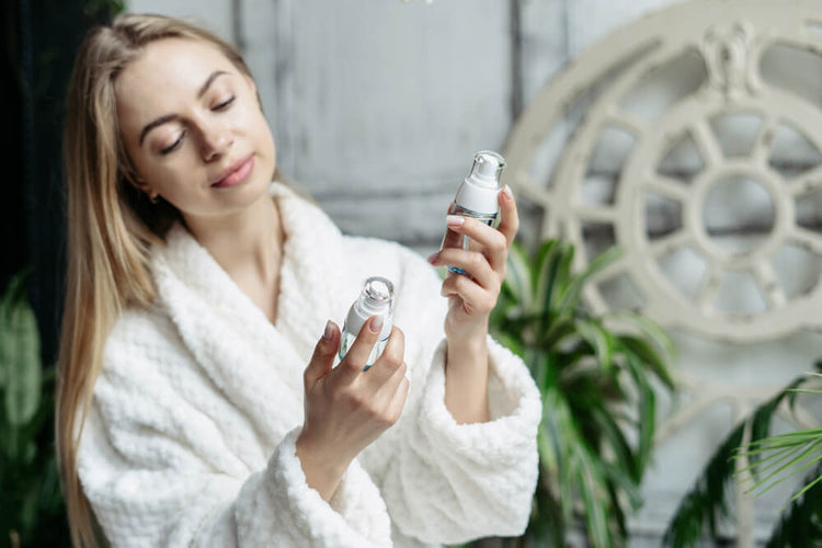 Woman in cozy robe examining natural skin care products for an effective skincare routine at home