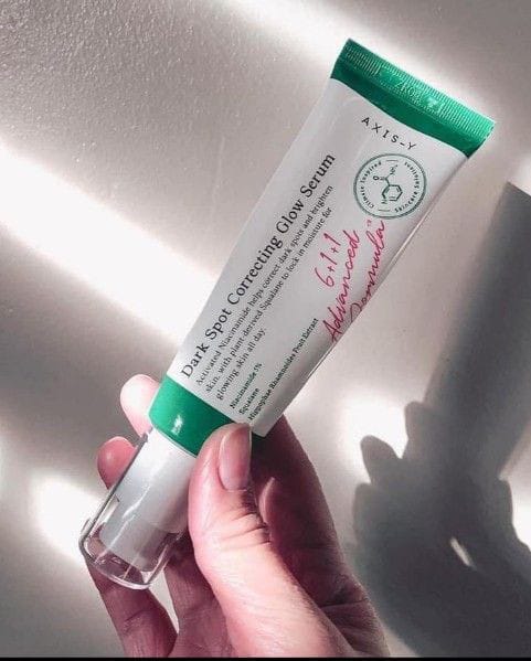 AXIS-Y dark spot serum in a tube held in hand, designed to correct dark spots and enhance natural glow